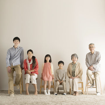 椅子に座り微笑む3世代家族