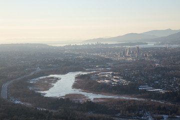 Aerial view of Burnaby Lake and the city in the background during a vibrant sunset. Taken in Greater Vancouver, British Columbia, Canada.