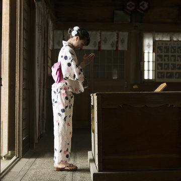 神社でお参りをする浴衣姿の女性