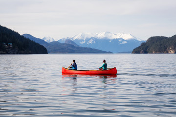 Fototapeta na wymiar Couple friends canoeing on a wooden canoe during a sunny day. Taken in Harrison Lake, East of Vancouver, British Columbia, Canada.