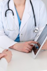  Closeup of a doctor and  patient  sitting at the desk. Physician pointing into tablet pc. Medicine and health care concept