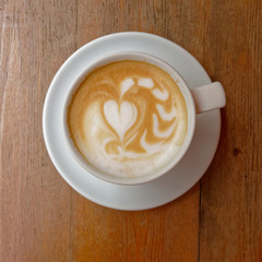 hot caffe latte cup on brown wood background, top view