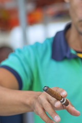 Cuban cigar in a man's hand against a light shirt