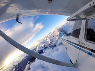 Obraz premium Small airplane flying over the Canadian Mountain Landscape during a vibrant sunset. Taken near Squamish, North of Vancouver, British Columbia, Canada.