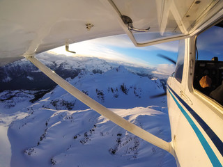 Small airplane flying over the Canadian Mountain Landscape during a vibrant sunset. Taken near...