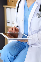 Woman doctor using white tablet computer while working in hospital