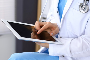 Woman doctor using white tablet computer while working in hospital