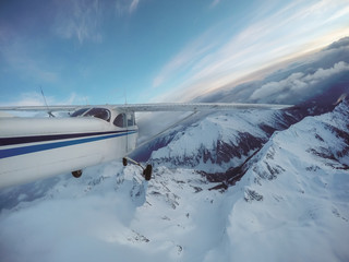 Small airplane flying over the Canadian Mountain Landscape during a vibrant sunset. Taken near Squamish, North of Vancouver, British Columbia, Canada.