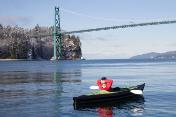 Adventurous man kayaking on an inflatable kayak near Lions Gate Bridge. Taken in North Vancouver, British Columbia, Canada.
