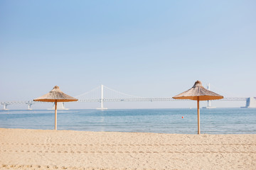 Sand beach. Beach straw umbrellas against the background of the blue sea and the sky.