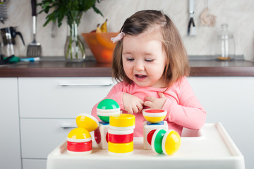 construction a 2 year old girl with long hair plays with a designer at home, builds towers, rejoices at successes