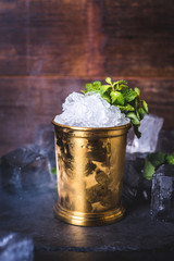 A tin can with ice is decorated with a sprig of mint. - 200615859