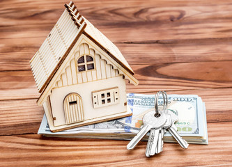 Keys with model of house and money on the wooden background. Real estate and mortgage concept.