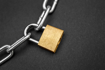 Golden padlock with chain on black background.