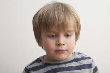 Fototapeta premium Niño (5 años) con cara seria mirando hacia abajo.