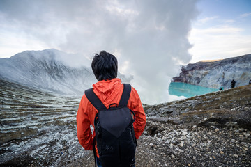 Young travler looking crater blue lake at Kawah Ijen, Indonesia