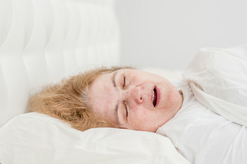Obraz na płótnie Canvas senior woman sleeping and snoring on the bed