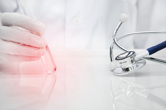 Stethoscope For Doctor Diagnosis With Hand Of Scientist In Glove And Lab Coat Holding Red Light Glass Test Tube In Medical Science Lab Background