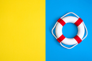 Lifebuoy on a yellow and blue background with blank space for text. Top view travel or vacation...