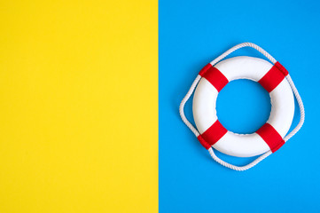 Lifebuoy on a yellow and blue background with blank space for text. Top view travel or vacation concept. Summer background. Flat lay photo, top view.
