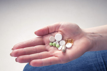 Multicolor pills in your palm, medications in woman's hand
