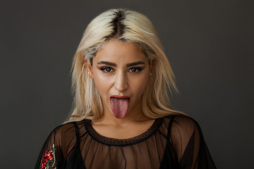 Beautiful blonde woman portrait wearing tulle shirt with tongue stuck out © patronestaff