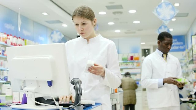 Two professional pharmacists working behind counter in modern pharmacy