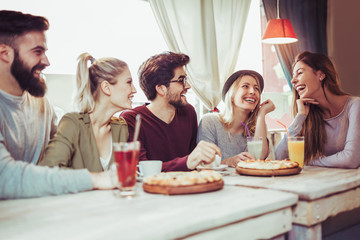 Young friends sharing pizza in a indoor cafe