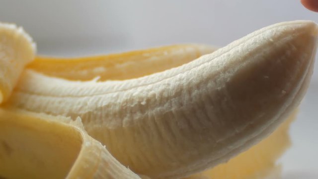 Woman sexually touching with a finger top of purified banana, macro close up view