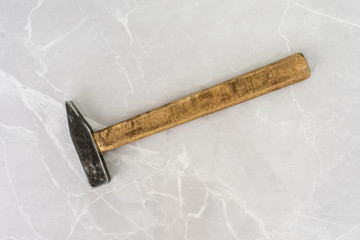 Old hammer on a light marble background.