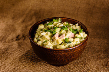 Ceramic bowl with russian traditional salad olivier on wooden table