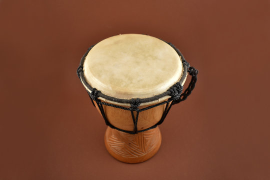 African drum stock images. Wooden drum with goat skin, ethnic musical instrument. Djembe Drum on a brown background