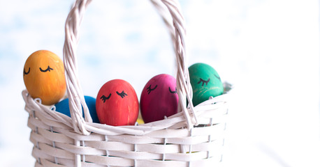Easter eggs in a white basket on a wooden background