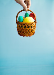 Basket with Easter eggs in hand on a blue background