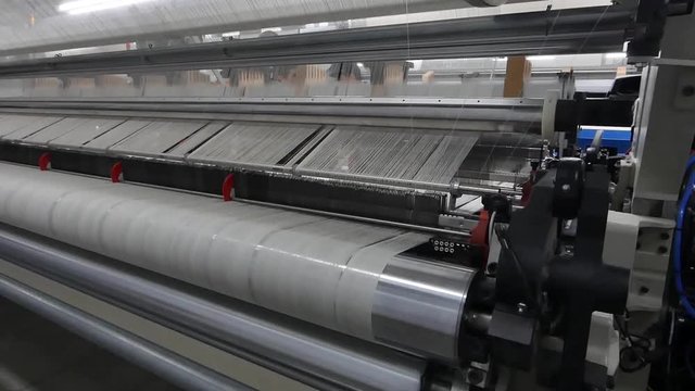 weaving loom at a textile factory, closeup. industrial fabric production line. the camera is stationary