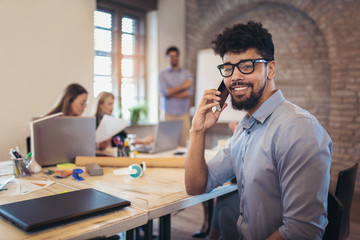 Business colleagues in conference meeting room during presentation. Businessman using phone and looking at camera.