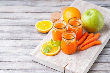Jars with carrot juice, apple, sliced orange and mint leaf 
