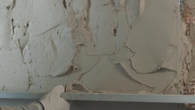 Slow motion handheld shot of worker leveling plaster on the wall