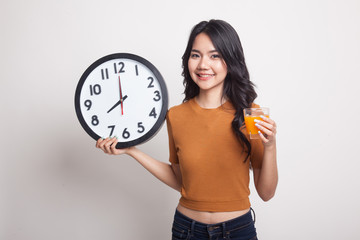 Asian woman with a clock drink orange juice.