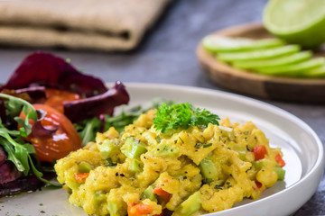 Scrambled eggs with pepper, avocado and parsley with saladdade witch eco spinach and rucola - close up.