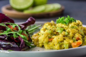 Scrambled eggs with pepper, avocado and parsley with saladdade witch eco spinach and rucola - close up.