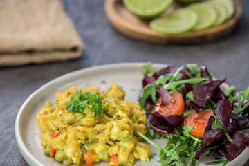 Scrambled eggs with pepper, avocado and parsley with saladdade witch eco spinach and rucola - close up.