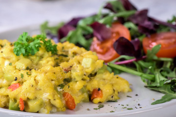 Scrambled eggs with pepper, avocado and parsley with saladdade witch eco spinach and rucola - close up.