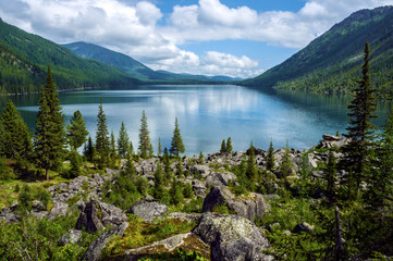 Lake in the mountains surrounded by old trees and large boulders. Wild remote place in the mountains. Huge boulders and old trees allow to forget about civilization.