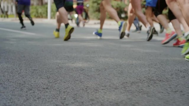 Action steadycam shot of group or pack or amateur athletes or professional runners during mrathon, unrecognizable sportsmen in sneakers run race or competition at sport event
