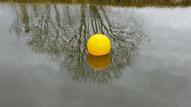 Bright yellow buoys with reflections on the surface of a canal.
