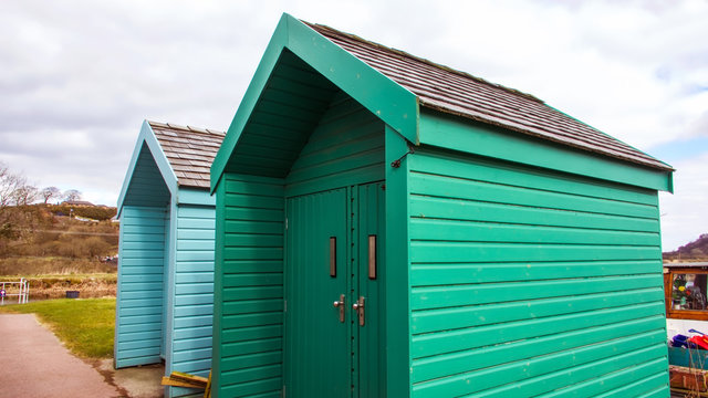 Green and blue painted wooden huts beside a canal.