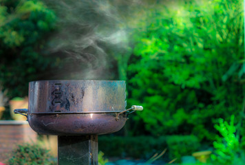 Ein rauchender Grill im Garten. Beim Grillen Ärger mit dem Nachbarn vermeiden.