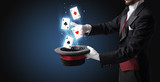 Magician with white gloves conjuring playing cards from a cylinder with magic wand