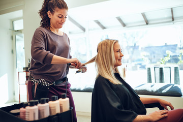 Smiling young woman having her hair styled in a salon